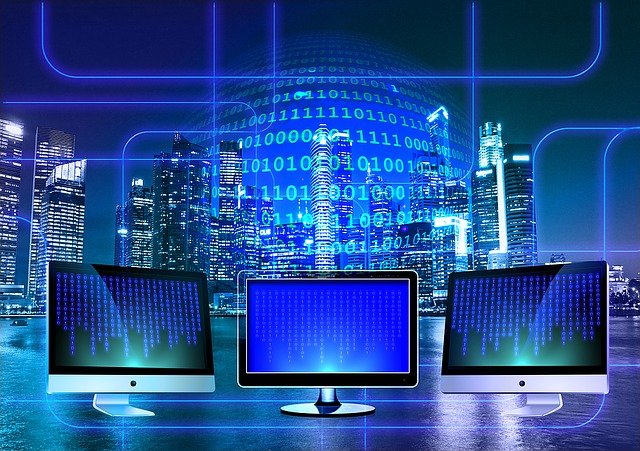 three computer screens sitting in front of skyscrapers with a blue graphic of ones and zeros